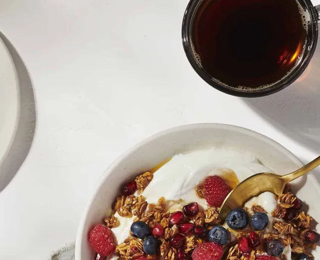 Cup of coffee and bowl of yogurt with fruit
